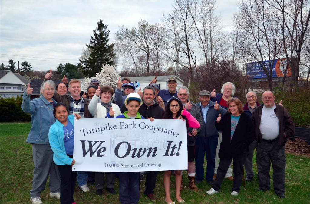 Turnpike Park Cooperative residents hold a banner saying "We Own It!"