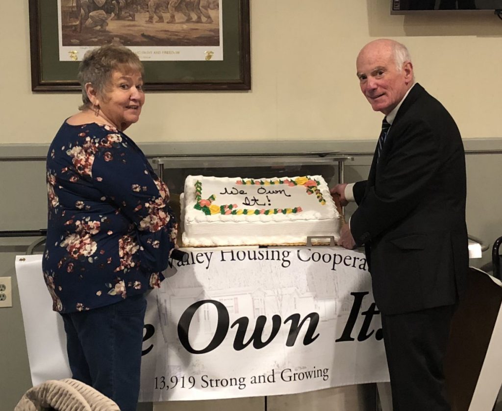 Two Sherwood Village residents pose with a cake saying "We Own It!" in frosting