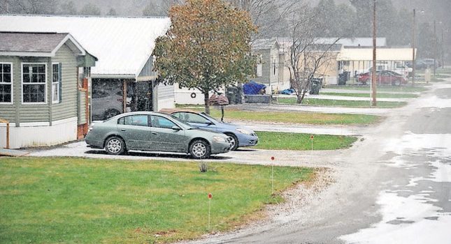A mobile home park with cars parked in driveways and snow on the ground