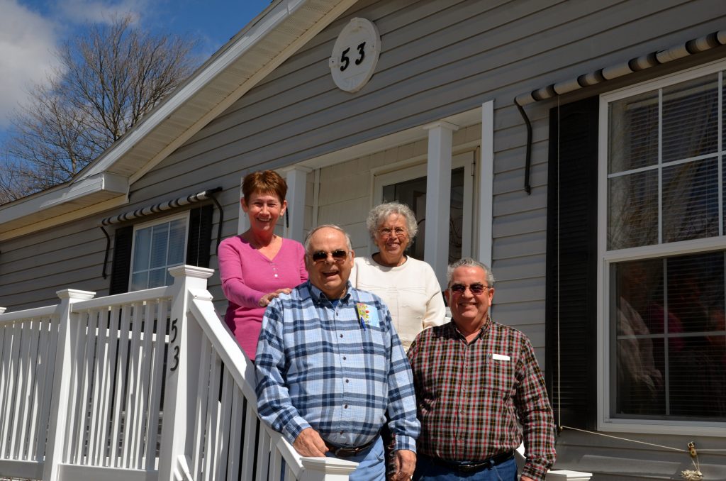 Members of the Heritage Association, Inc. Board of Directors standing on the steps in front of their community building. In the back, left to right: Gail Lavalle, treasurer, and Susan Johnson, board member. In the front: Dennis Morel, secretary, and Herb Kingston, board member.